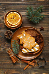 Naklejka premium Plate with tasty Christmas cookies and decor on brown wooden background