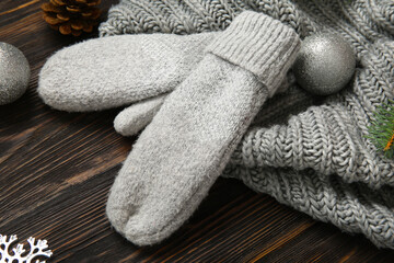 Warm mittens, scarf and Christmas decorations on wooden background, closeup
