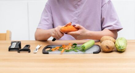 Close-up shot of a woman peeling vegetables using special vegetable peelers in the kitchen	