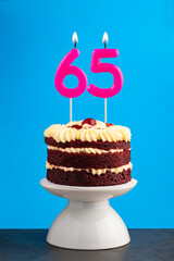 Red velvet birthday cake with number 65 candle