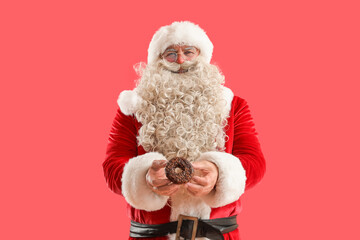 Santa Claus with tasty donut on red background