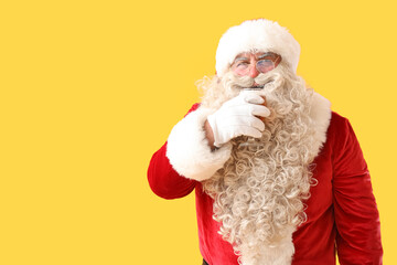 Santa Claus with glass of beer on yellow background