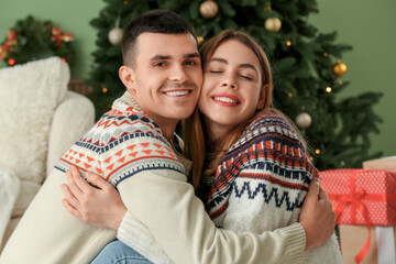 Young couple hugging in living room decorated for Christmas