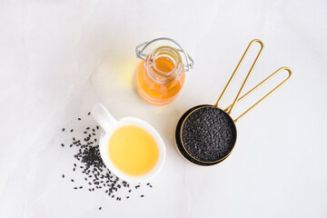 Bottle and spoon of oil with sesame seeds on white background