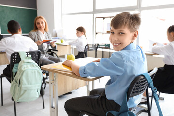 Obraz premium Little schoolboy having lesson in classroom, closeup