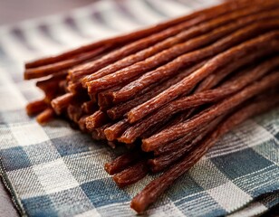 close up of thin brown meat sticks stacked on a table