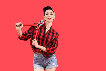 Young pin-up woman with pipe wrench on red background