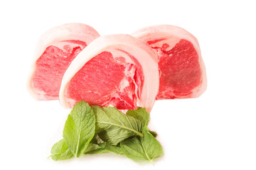 Fresh uncooked lamb loin chops and mint leaf on white background. High quality meat product cut by butcher in perfect size for cooking. Food supply chain and agriculture industry.