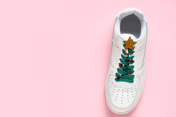 Stylish sneaker with shoelace in shape of Christmas tree on pink background