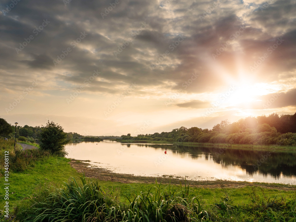Wall mural beautiful sunset scene with lake and trees and stunning cloudy sky. calm and relaxing mood. castleba