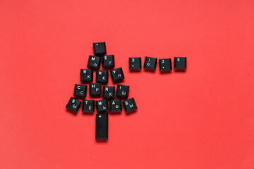 Christmas tree made of black computer keys on red background