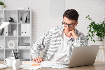 Male economist working with diagrams at table in office