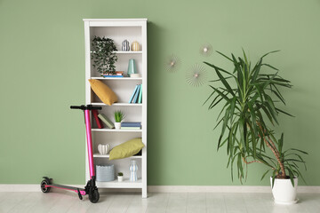 Interior of room with electric scooter, shelf unit and palm tree