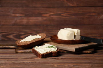 Boards with fresh butter and bread on wooden background