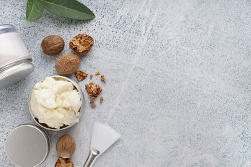Jars of shea butter with nuts and brush on grunge background