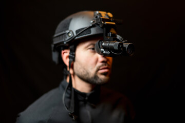 Soldier in tactical military helmet with night vision device on black background, soft focus photo.