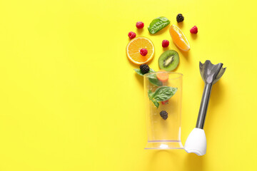 Modern blender with fruits and berries on yellow background