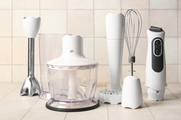 Modern blender with different attachments on white tile background