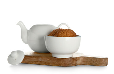 Teapot and bowl with cookies on board against white background