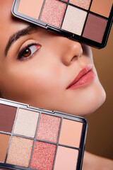 Cropped vertical photo of passionate shiny girl showing you eyeshadows palettes isolated brown...