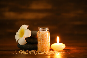Spa composition with sea salt and burning candle on dark wooden table, closeup