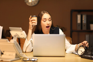 Shocked businesswoman with coffee cup and alarm clock trying to meet deadline in office at night