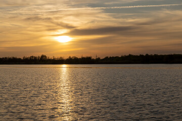 orange sunset is reflected in the water of the lake