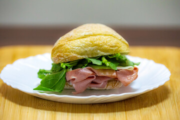 Italian mortadella bologna sandwich with arugula, tomato and cheese on ciabatta bread