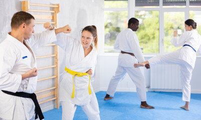 Irate middle-aged female karate practitioner fighting with her opponent in sports hall