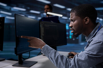 Server hub technician frowning, confused by errors on screen while shielding data from potential...