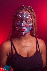 Woman with face painted with colorful paint and braids in her hair posing for a photo.