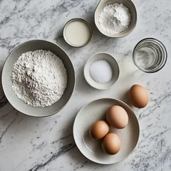 Fotobehang a white and grey marble table with the following ingredients laid out: flour in a bowl, baking powder in a plate, Salt in a plate, Eggs, sugar in a bowl and water in a bowl © Nelover