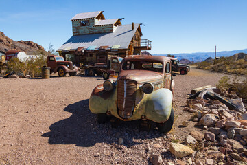 Abandoned vintage rusted vehicles in a desert junkyard
