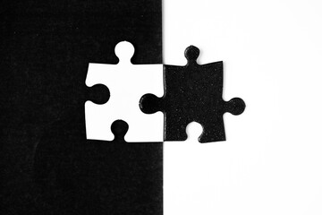 Opposite day concept using white and black puzzle pieces with oposite background color. Similar to a yin yang symbol.