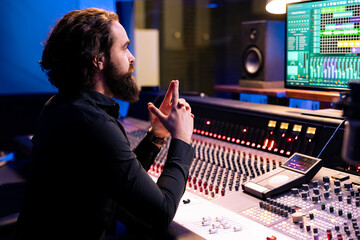 Tracking expert processing new songs with digital audio software and mixing console in studio,...