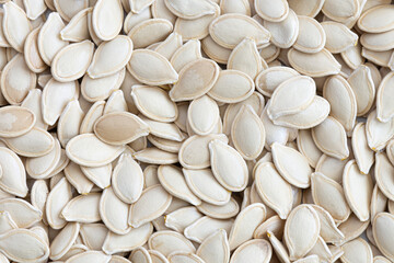 A top view image of a pile of fresh unshelled pumpkin seeds.