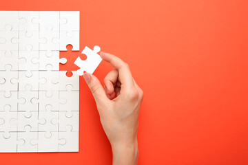 Woman solving white puzzle on red background, closeup. Space for text