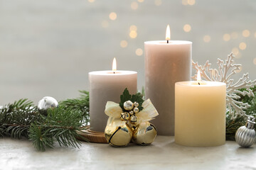 Burning candles, baubles and fir tree branches on white textured table, closeup