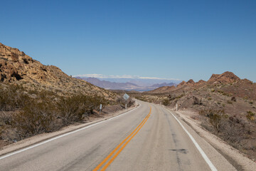 Two lane road through the desert with mountains in background