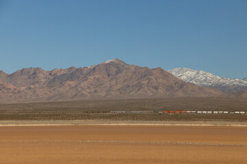 Long train in the desert with mountain background