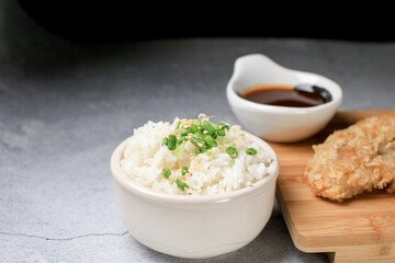Steamed rice with black sesame seeds and spring onion in ceramic bowl on table. Japanese and Asia eat with food