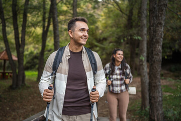 Man hiker backpacker explore scenic forest with hiking sticks