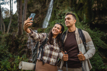 Naklejka premium hiker couple backpackers take a self portrait around waterfall