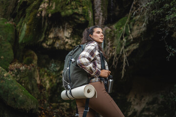 back view of adult woman hiker in front cave in the forest