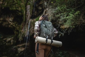 back view of adult woman hiker in front cave in the forest