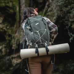 back view of adult woman hiker in front cave in the forest