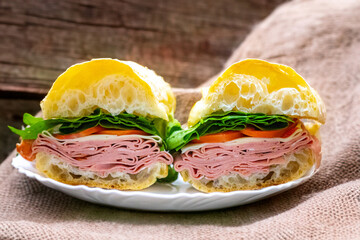 Italian mortadella bologna sandwich with arugula, tomato and cheese on ciabatta bread