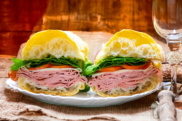 Italian mortadella bologna sandwich with arugula, tomato and cheese on ciabatta bread