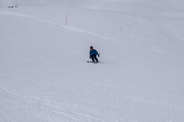 Young male skier in action skiing downhill in a European ski resort. Side view of skier descending in Les Menuires winter resort, France.