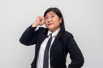 With a playful look, the woman mimics a gesture of thinking, placing one finger near her temple while looking upward. Her expression is lighthearted, mixing curiosity with humor.